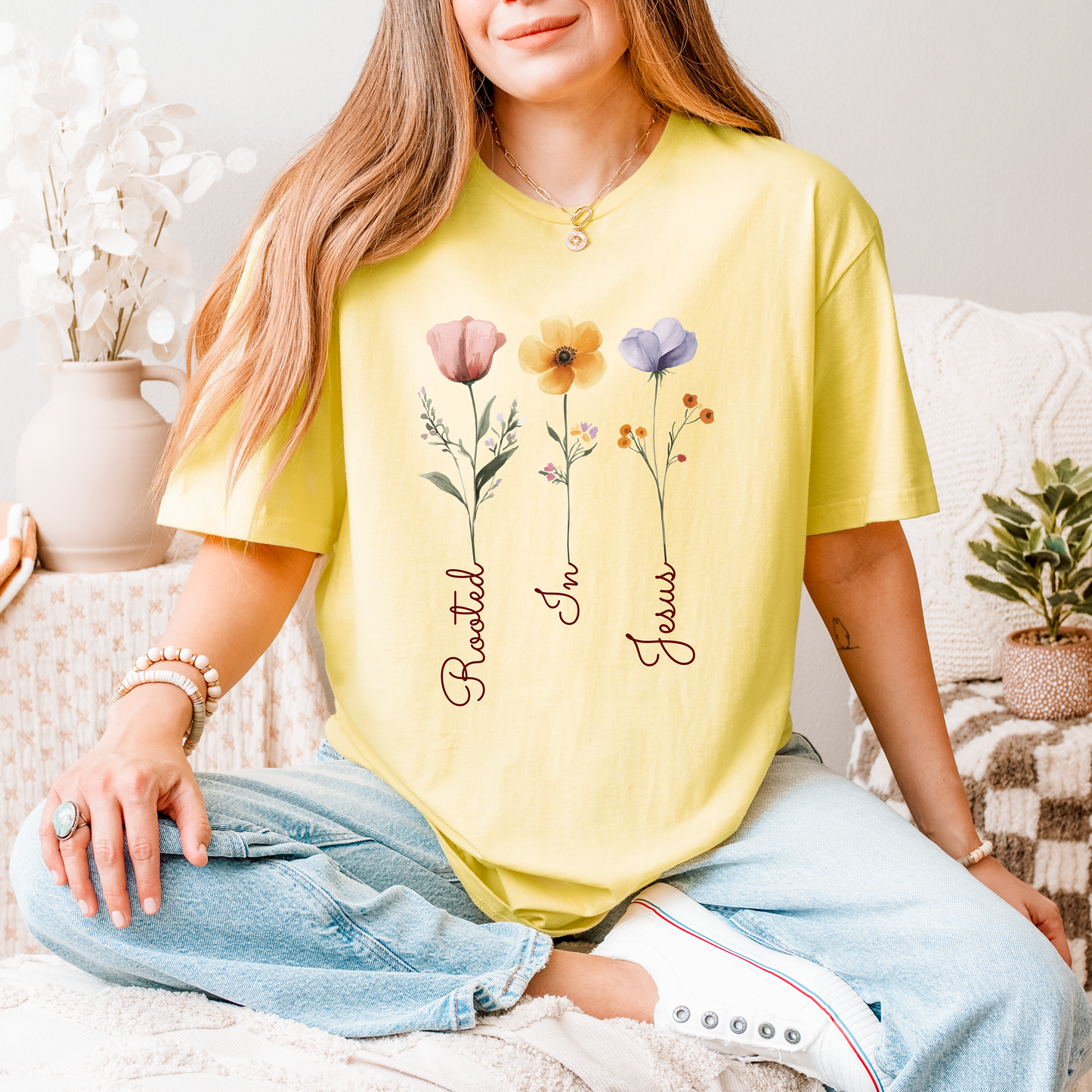 A YELLOW TSHIRT THAT SAYS ROOTED IN JESUS AND HAS FLOWERS ON IT